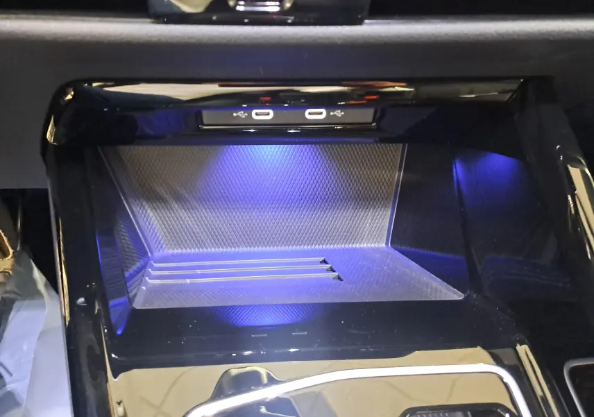 Gros plan sur la zone de rangement avant avec éclairage bleu et ports USB dans une Volkswagen Golf 2.0 TDI 2024 noire.