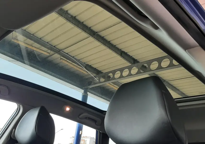 Vue intérieure du toit ouvrant panoramique du Renault Kadjar bleu Iron 2020, avec appuis-tête en cuir noir visibles.