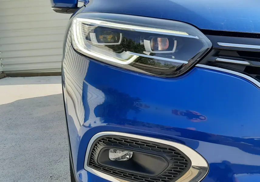 Gros plan sur l'avant gauche du Renault Kadjar 2020 bleu Iron, mettant en valeur le phare et le feu antibrouillard.