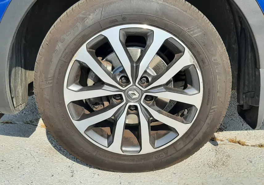 Gros plan sur la roue avant gauche d’un Renault Kadjar bleu iron 2020 avec jante alliage distinctive.