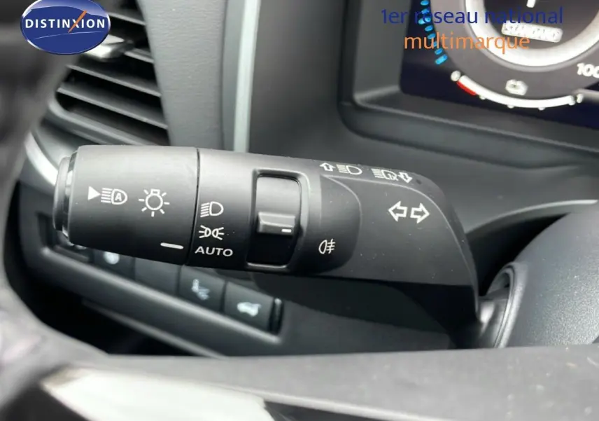 Gros plan sur la commande des feux et clignotants à gauche du volant dans un Nissan Qashqai blanc nacré 2025.