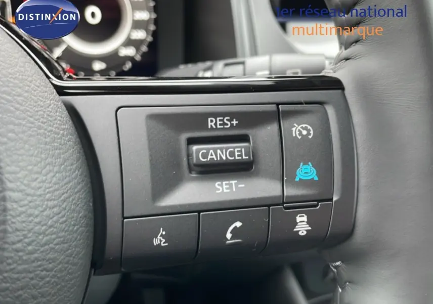 Gros plan sur les commandes au volant du Nissan Qashqai blanc nacré, mettant en valeur les boutons de régulateur de vitesse et assistance conduite.