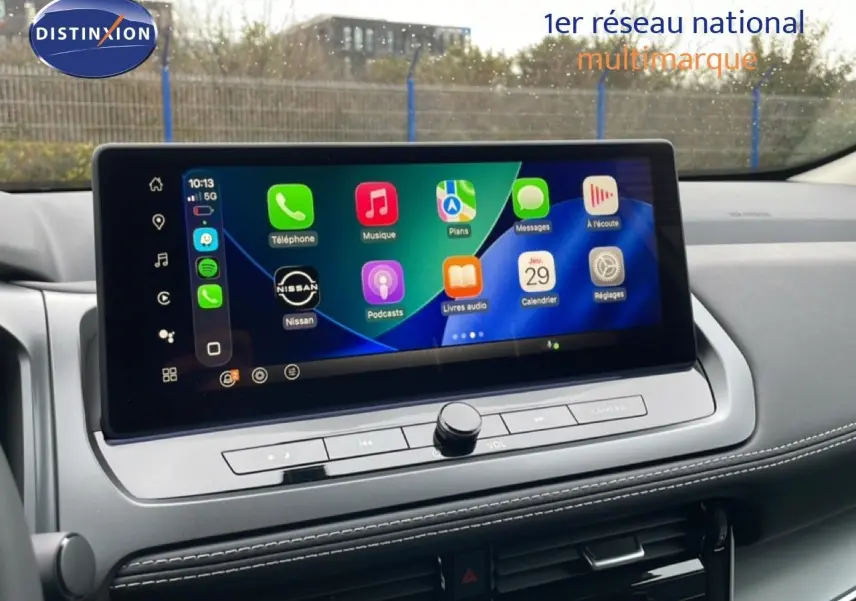 Écran tactile central du Nissan Qashqai 2025 affichant l’interface Apple CarPlay, avec tableau de bord gris et coutures blanches.