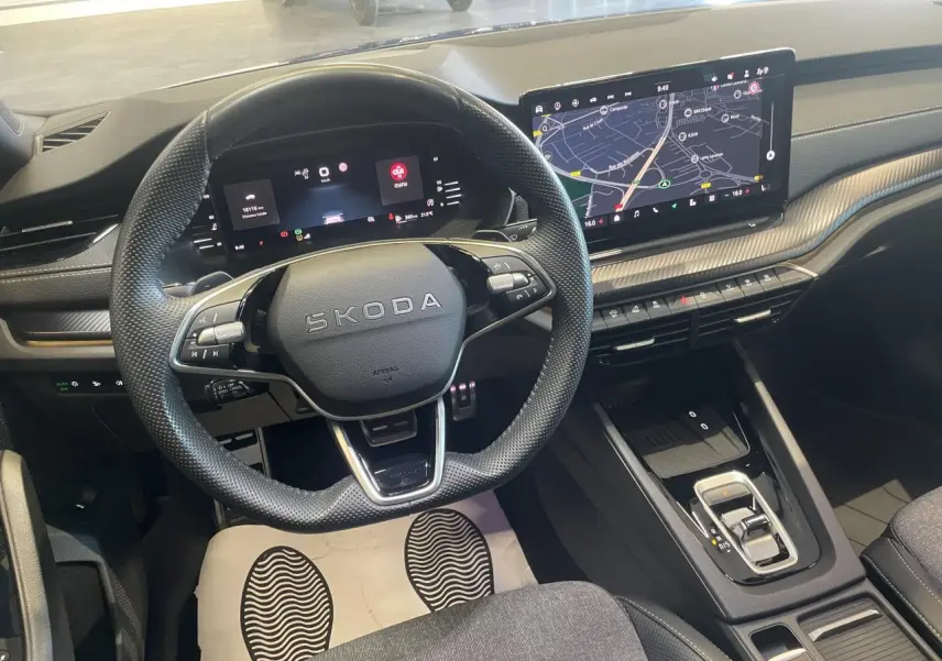 Vue intérieure avant de la Skoda Octavia 2025 bleu foncé, volant sport, tableau de bord numérique et écran tactile central.