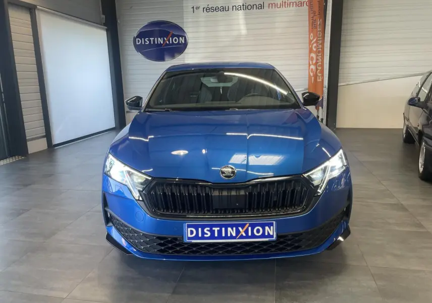 Vue frontale d'une Skoda Octavia Sportline bleu foncé avec calandre noire et phares LED allumés en showroom.