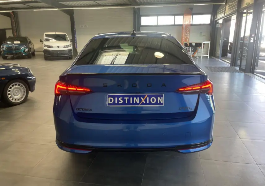 Vue arrière d'une Skoda Octavia bleu foncé avec feux arrière LED allumés dans un showroom.
