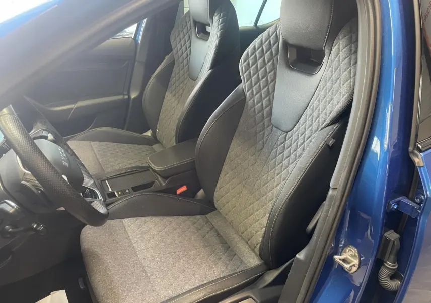 Intérieur avant de la Skoda Octavia bleu foncé 2025, sièges sport gris avec surpiqûres losanges et volant cuir.