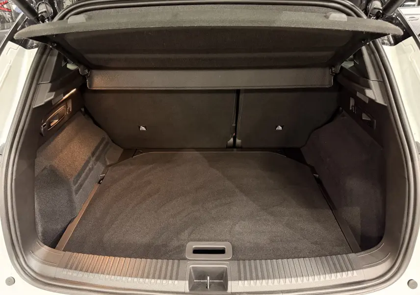 Coffre ouvert vu de l'arrière d'un Renault Austral blanc nacré avec toit noir, montrant un espace de chargement propre et spacieux.