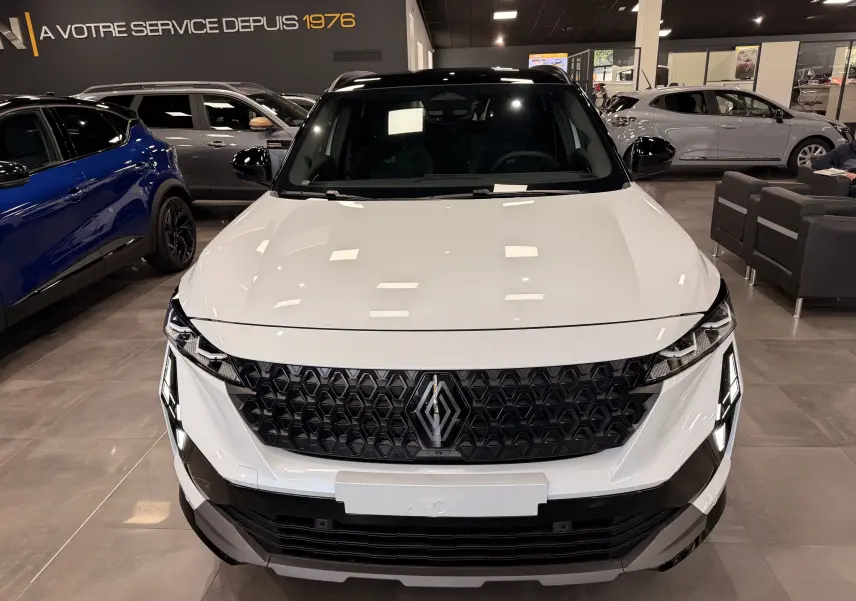Vue frontale d’un Renault Austral blanc nacré avec toit noir, calandre noire à motif hexagonal et éclairage LED distinctif.