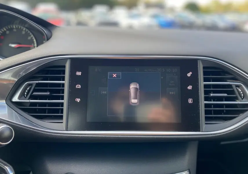 Écran tactile central du tableau de bord de la Peugeot 308 gris aluminium avec affichage de l'aide au stationnement.