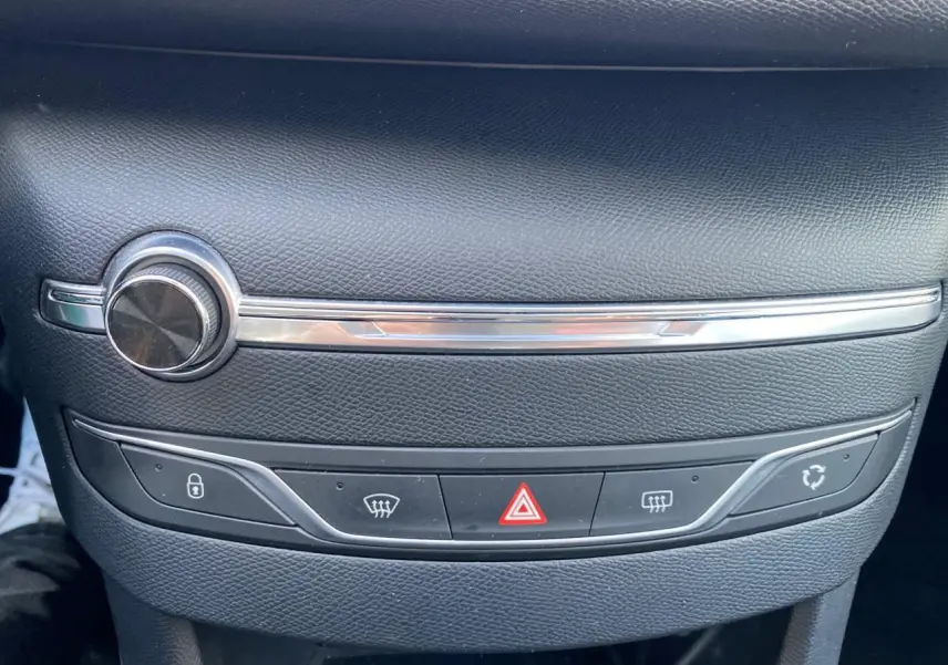 Gros plan sur la console centrale de la Peugeot 308 gris aluminium, avec commandes de climatisation et bouton de verrouillage.