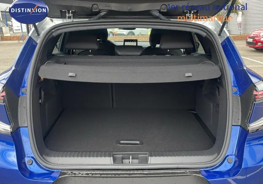 Coffre ouvert d'un Renault Captur E-Tech hybride bleu Iron Metal avec toit gris, vue arrière montrant l'espace de chargement.