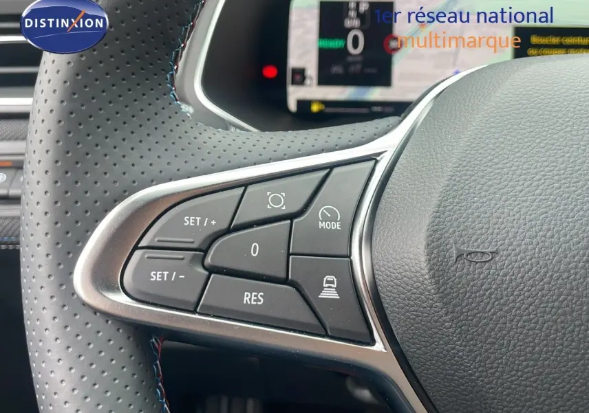Gros plan sur les commandes au volant en cuir perforé du Renault Captur E-Tech hybride 2025, affichage numérique en arrière-plan.