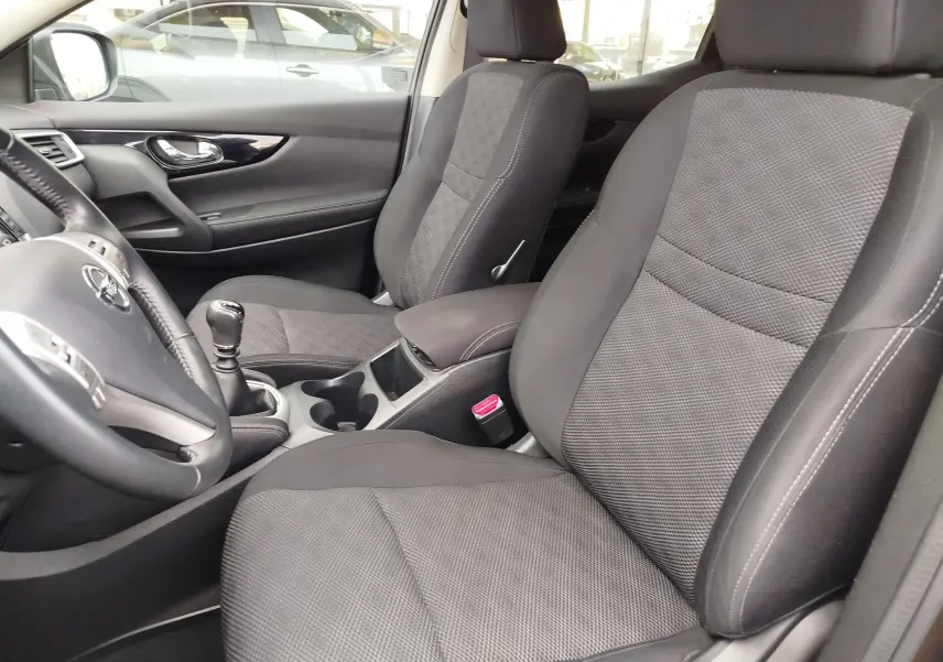 Vue intérieure côté conducteur du Nissan Qashqai 2017, tableau de bord noir avec écran tactile et boîte manuelle.