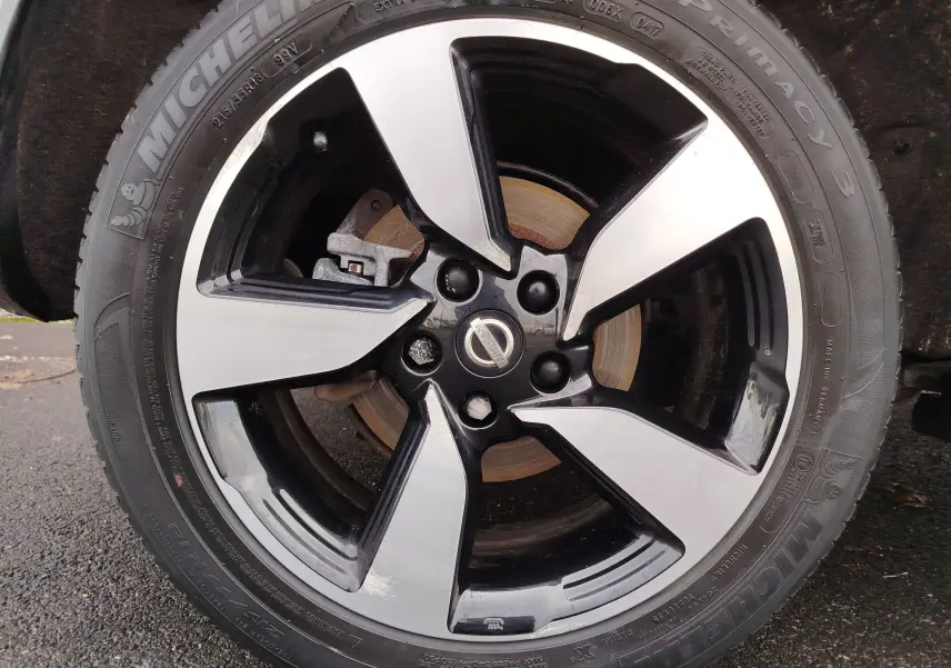 Gros plan sur la jante alliage bicolore noir et argent avec logo Nissan, montée sur un pneu Michelin.