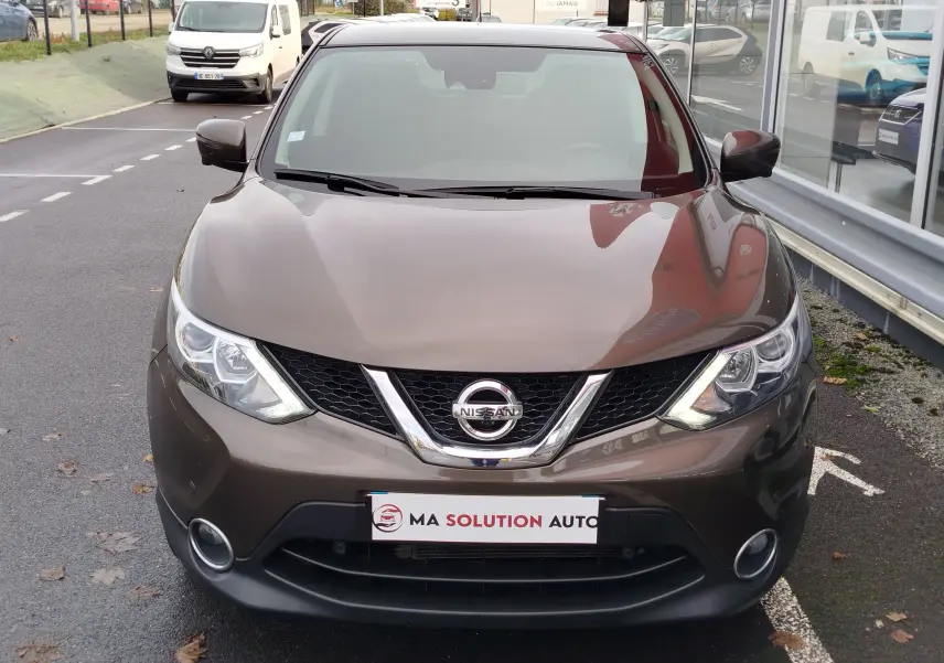 Vue avant d'un Nissan Qashqai bronze Ultime 2017, mettant en valeur sa calandre et ses phares LED allumés.