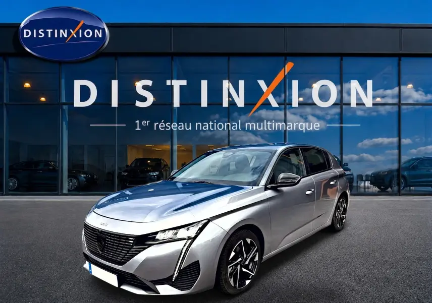 Peugeot 308 gris artense vue 3/4 avant droit, avec calandre noire et jantes alliage distinctives.