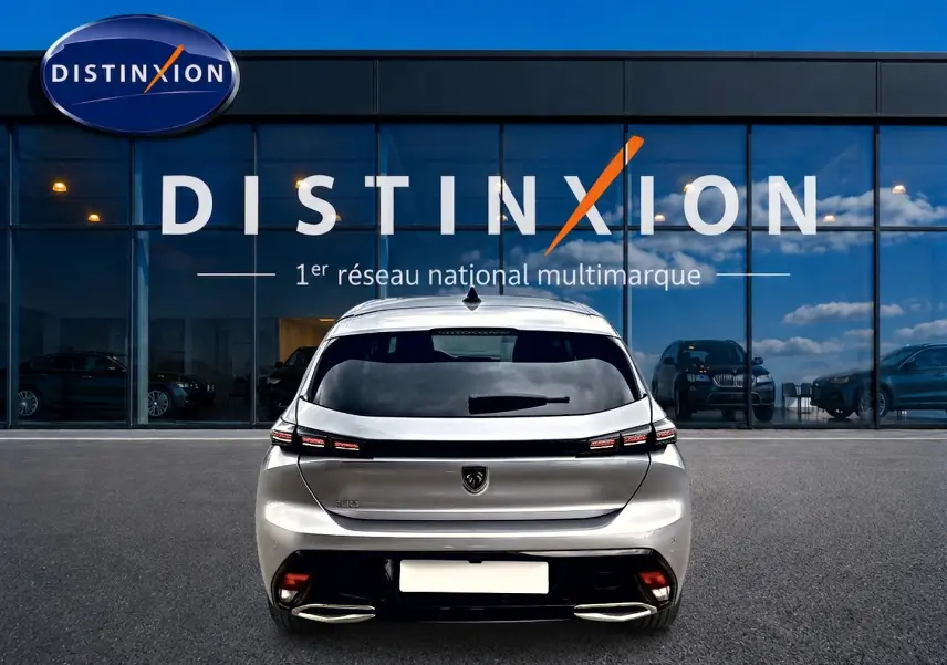 Vue arrière d'une Peugeot 308 gris artense garée devant une vitrine avec logo Distinxion.