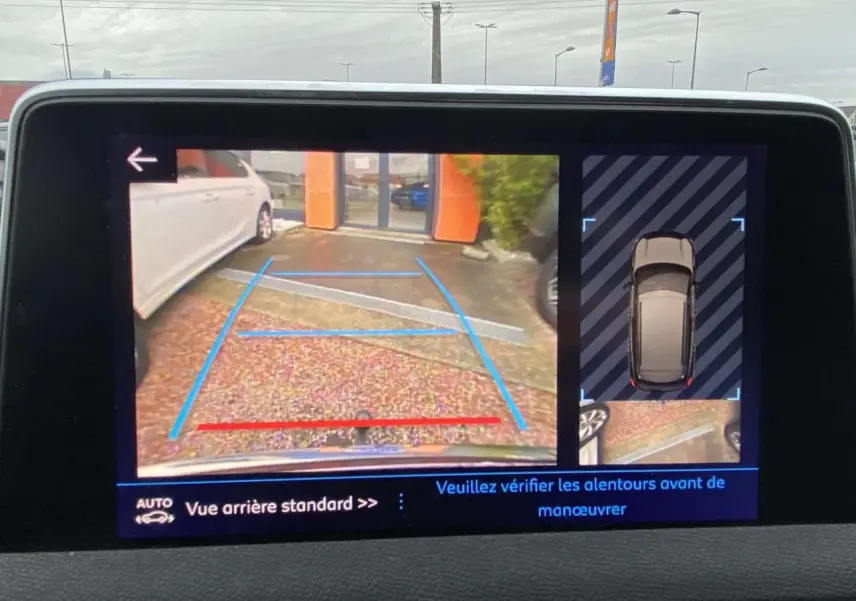 Écran tactile du Peugeot 3008 montrant la caméra de recul avec vue arrière et vue de dessus du véhicule marron foncé.