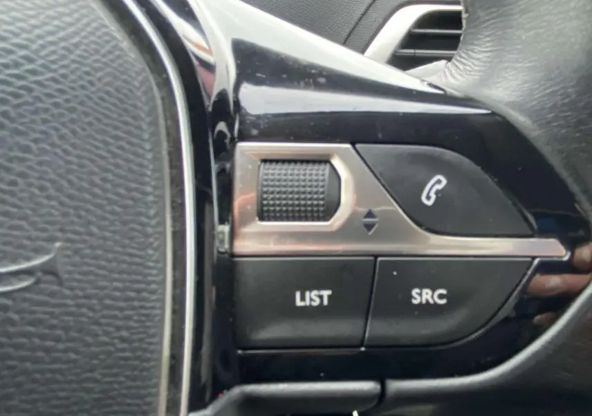 Gros plan sur les commandes multifonctions du volant noir du Peugeot 3008 marron foncé de 2017.