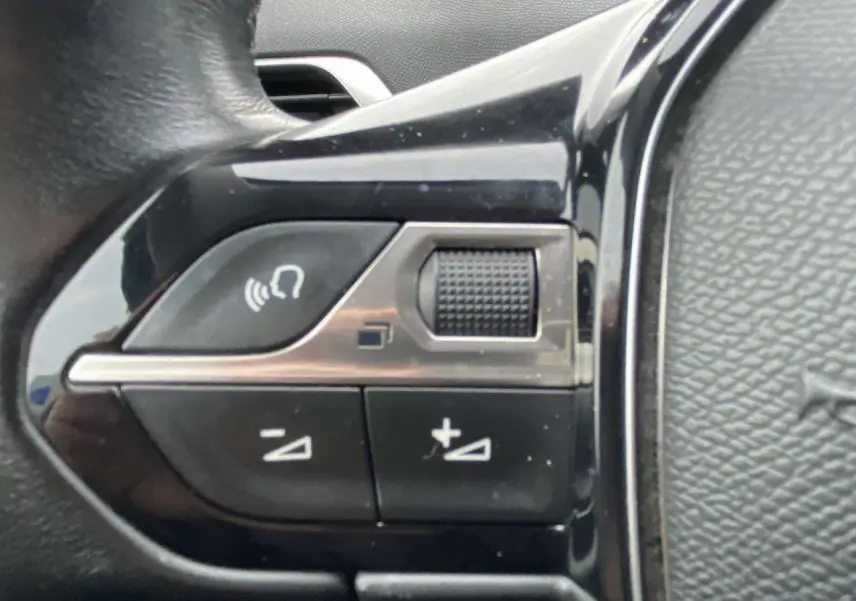 Gros plan sur les commandes de volume au volant du Peugeot 3008 marron foncé de 2017.