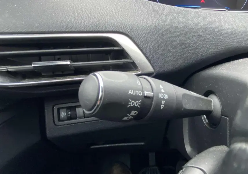 Gros plan sur la commande des feux du tableau de bord du Peugeot 3008 marron foncé, version 2017 Allure.