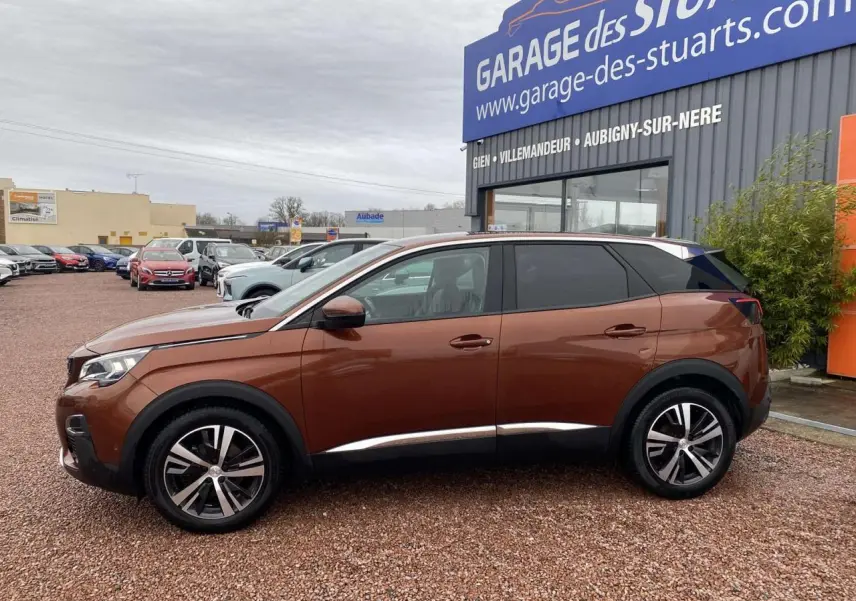 Profil côté gauche du Peugeot 3008 marron foncé avec jantes alliage 18 pouces, stationné devant un garage.