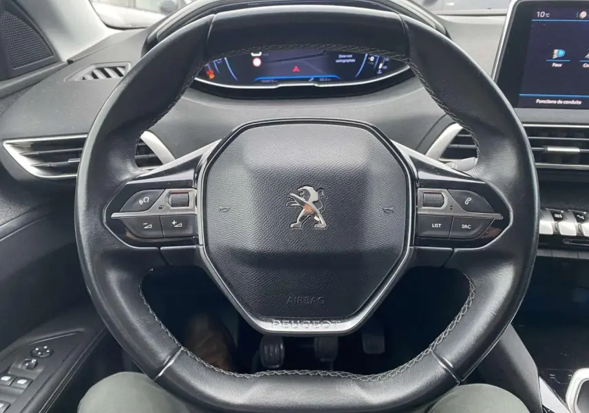 Vue rapprochée du volant compact en cuir noir du Peugeot 3008 avec commandes intégrées et tableau de bord numérique.