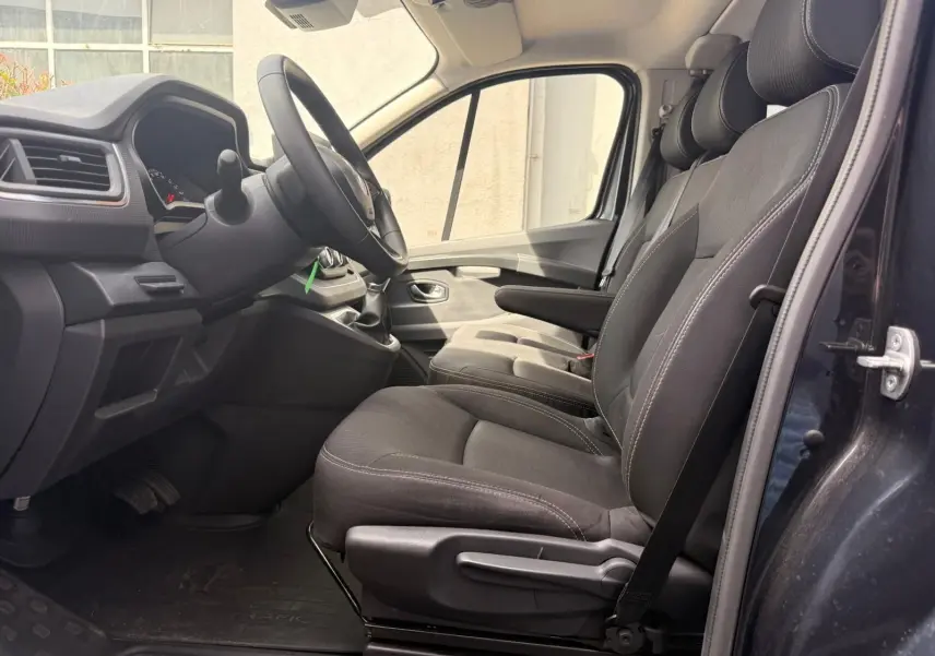 Vue intérieure côté conducteur du Renault Trafic cabine approfondie 2024, sièges tissu gris et tableau de bord sobre.