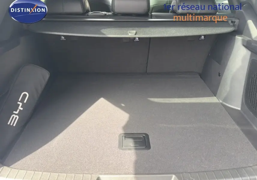 Coffre spacieux vu de l'arrière d'un BYD SEAL U blanc métal, avec tapis gris et cache-bagages déployé.
