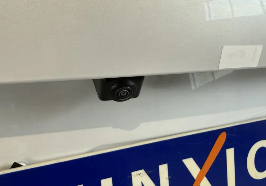 Gros plan sur la caméra de recul noire sous la malle arrière d’un BYD SEAL U blanc métal, près de la plaque d’immatriculation.