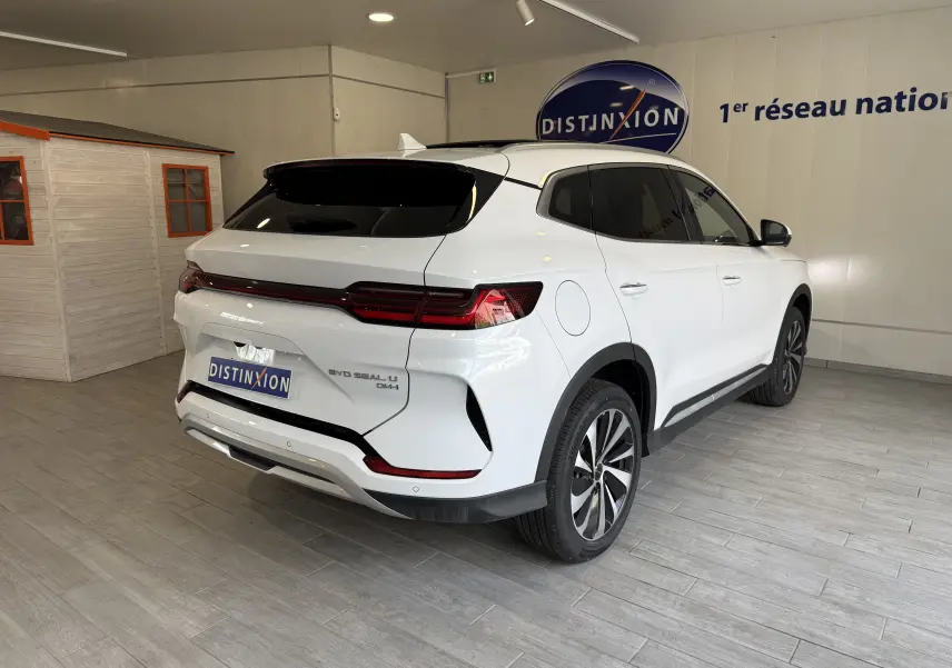 Vue 3/4 arrière droite du BYD SEAL U blanc métal avec feux arrière LED et jantes bi-ton dans un showroom.