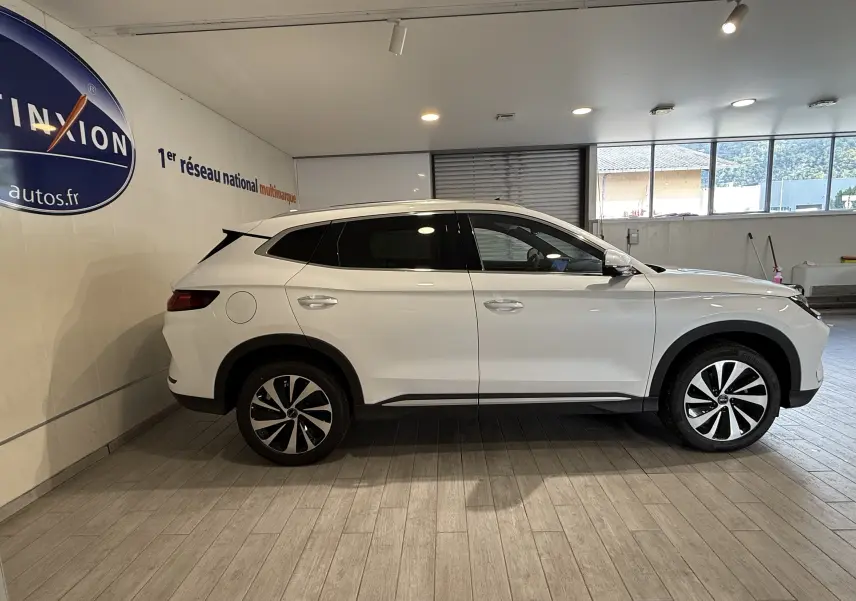 Vue de profil côté gauche d'un SUV BYD SEAL U blanc métal, avec jantes bicolores et vitres teintées, en intérieur showroom.