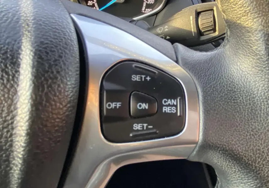 Gros plan sur les commandes du régulateur de vitesse au volant d'une Ford B-MAX blanche de 2014.