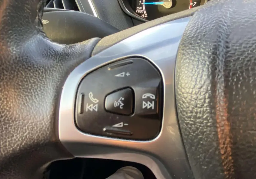 Gros plan sur les commandes vocales et audio au volant du Ford B-MAX blanc 2014, version Titanium.