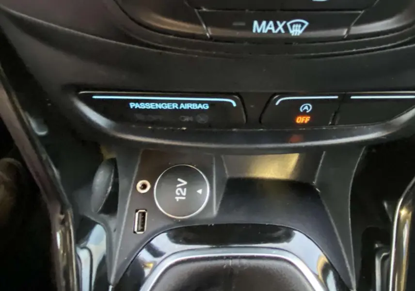 Gros plan sur la console centrale du Ford B-MAX blanc 2014, montrant prise 12V, port USB et commandes d'airbag passager.