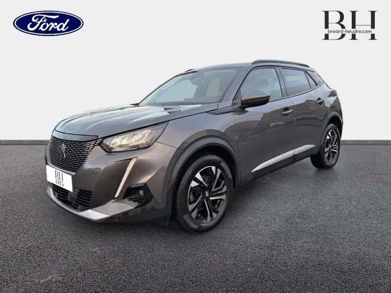 Peugeot 2008 gris Artense vue 3/4 avant droit avec jantes alu et barres de toit visibles sur fond neutre.