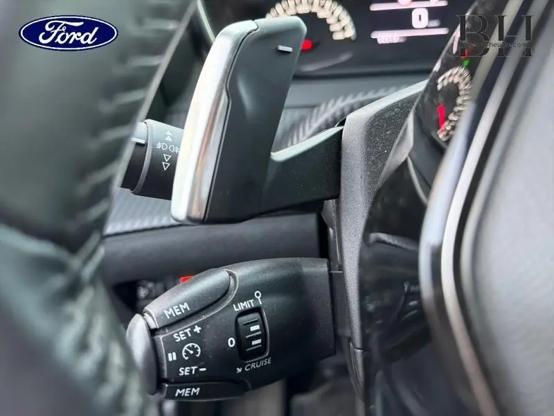 Gros plan sur le commodo de régulateur de vitesse et palette au volant d'un Peugeot 2008 gris Artense.