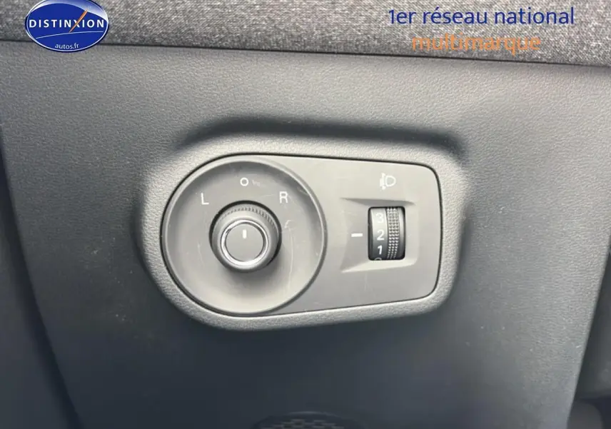 Gros plan sur les commandes de réglage des rétroviseurs et des phares du MG ZS Hybrid blanc, côté conducteur.