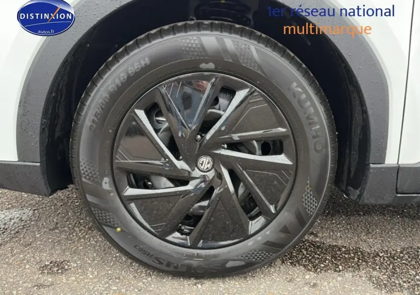 Gros plan sur la roue avant droite du MG ZS blanc, mettant en valeur la jante noire brillante au design moderne.