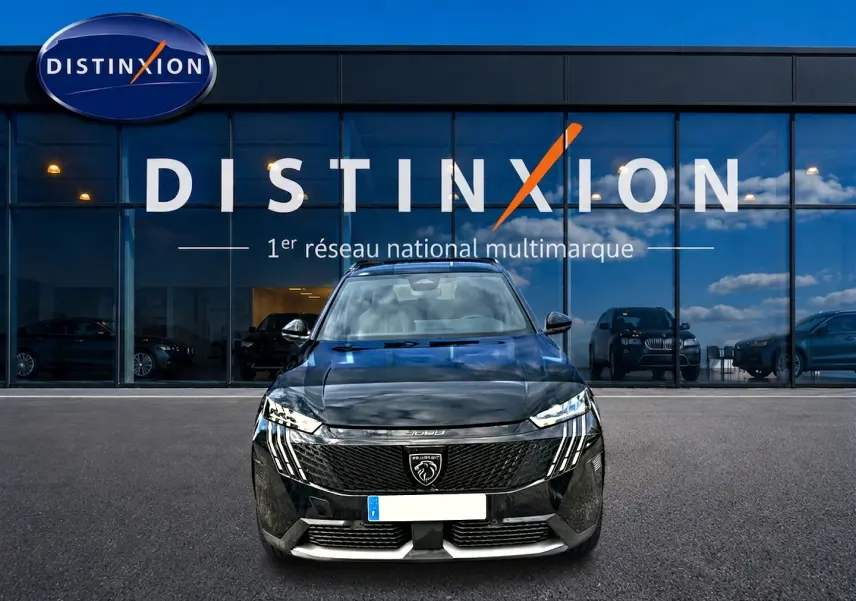 Vue avant d'un Peugeot 5008 Hybrid 145 GT noir, avec calandre distinctive et phares LED verticaux, devant un showroom Distinxion.