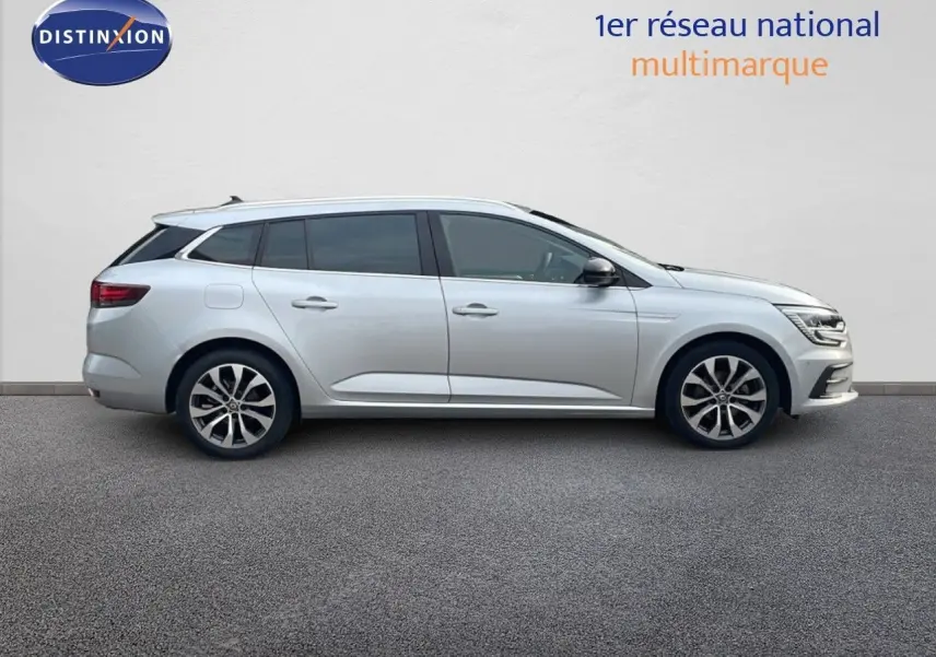 Profil latéral droit d'une Renault Mégane Break 2024 gris Highland Metal avec jantes alliage bicolores.