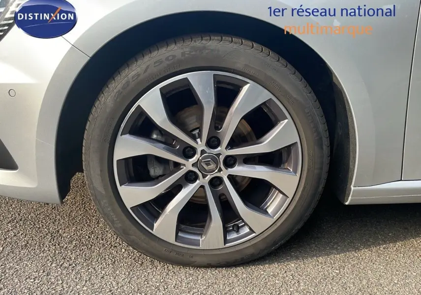 Gros plan sur la roue avant gauche de la Renault Mégane Break gris Highland Metal avec jante alliage bi-ton.