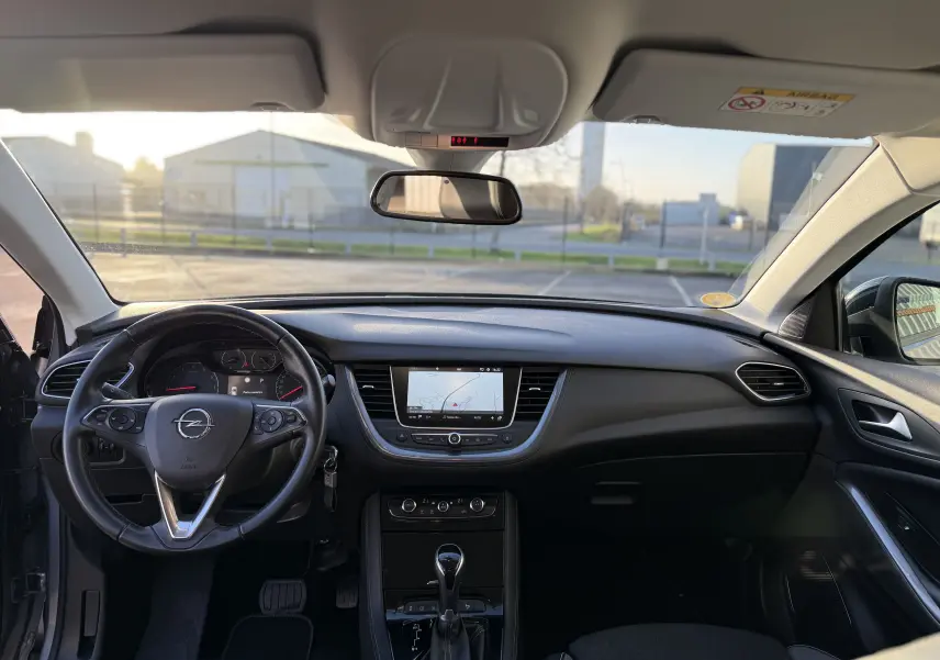 Vue intérieure avant de l'Opel Grandland X 2019 montrant le tableau de bord noir et le volant multifonction avec écran tactile central.