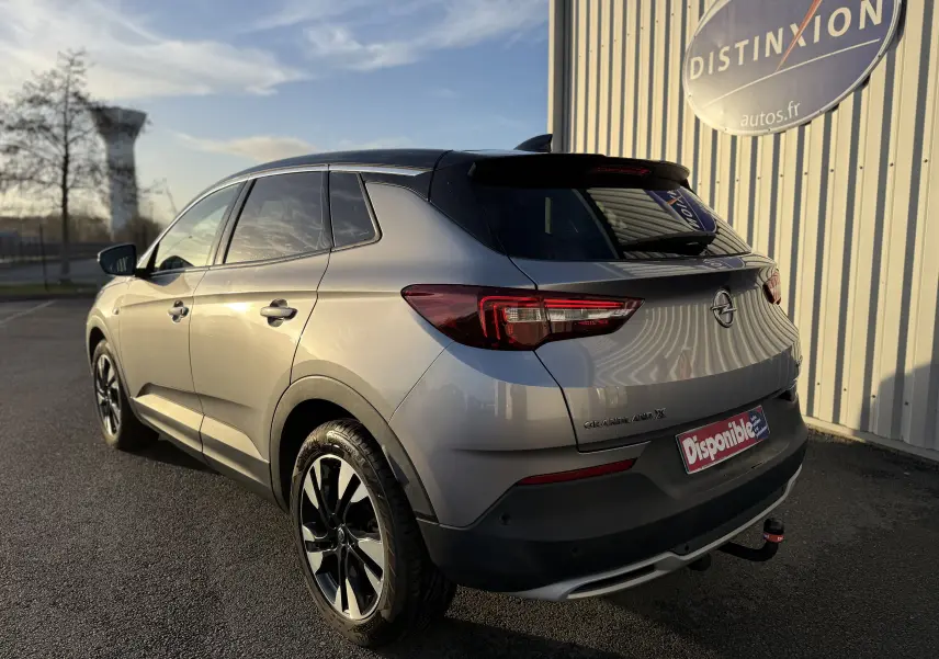 Opel Grandland X gris quartz vu en 3/4 arrière droit, avec jantes noires et toit noir contrastant.