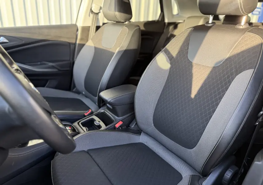Intérieur de l'Opel Grandland X 2019, vue rapprochée des sièges avant en tissu noir et gris avec surpiqûres.