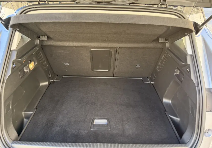 Coffre ouvert vu de l'arrière d'un Opel Grandland X gris quartz, montrant un espace de chargement propre et bien agencé.