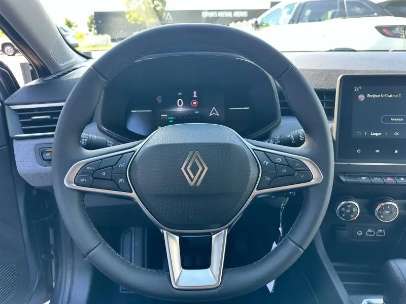 Vue centrée sur le volant multifonction noir avec logo Renault, tableau de bord numérique et écran tactile à droite.