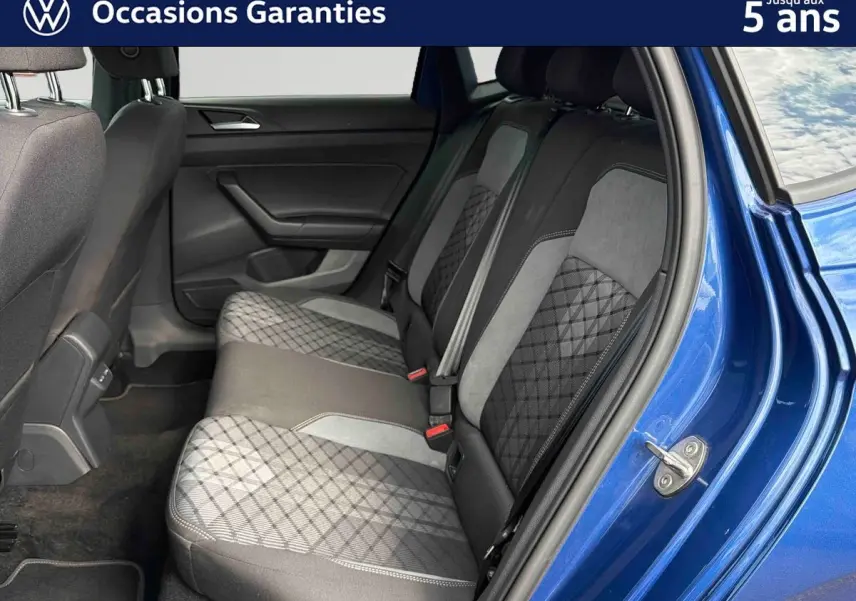 Vue côté droit des sièges arrière en tissu gris à motifs géométriques d'une Volkswagen Polo bleue 2025 avec porte ouverte.