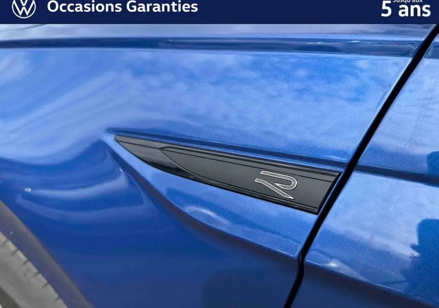 Détail de l'aile avant gauche bleu métallisé avec logo "R" noir sur Volkswagen Polo 2025.